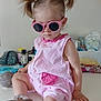toddler, child, sunglasses, pink_romper, pigtails, indoor, table, footwear, casual, baby, cute, fashion, accessory, hair_style, sitting, person, home, relaxed, funny, portrait