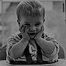 Tiago participe au concours pour gagner de l'argent avec cette photo : child, toddler, high_chair, smiling, black_and_white, indoor, cute, clothing, baby, person, face, hands, seat, playful, portrait, sitting, young, infant, expression, home