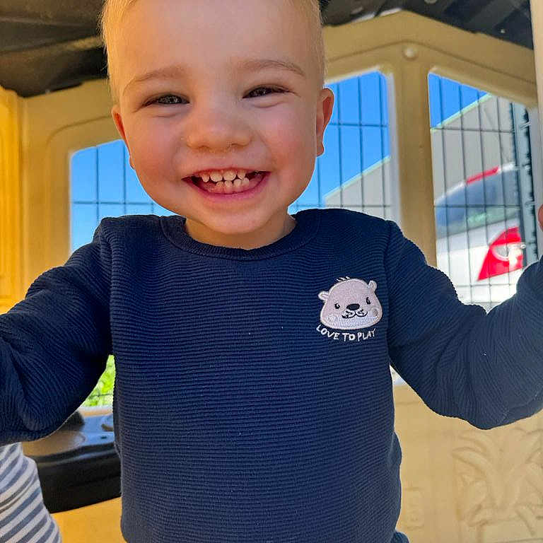 Tiago participe au concours pour gagner de l'argent avec cette photo : child, toddler, smiling, playground, blue_sweater, happy, face, outdoor, sunny, play, cute, young_child, casual_clothing, daylight, person, portrait, joyful, fun, colorful, play_structure