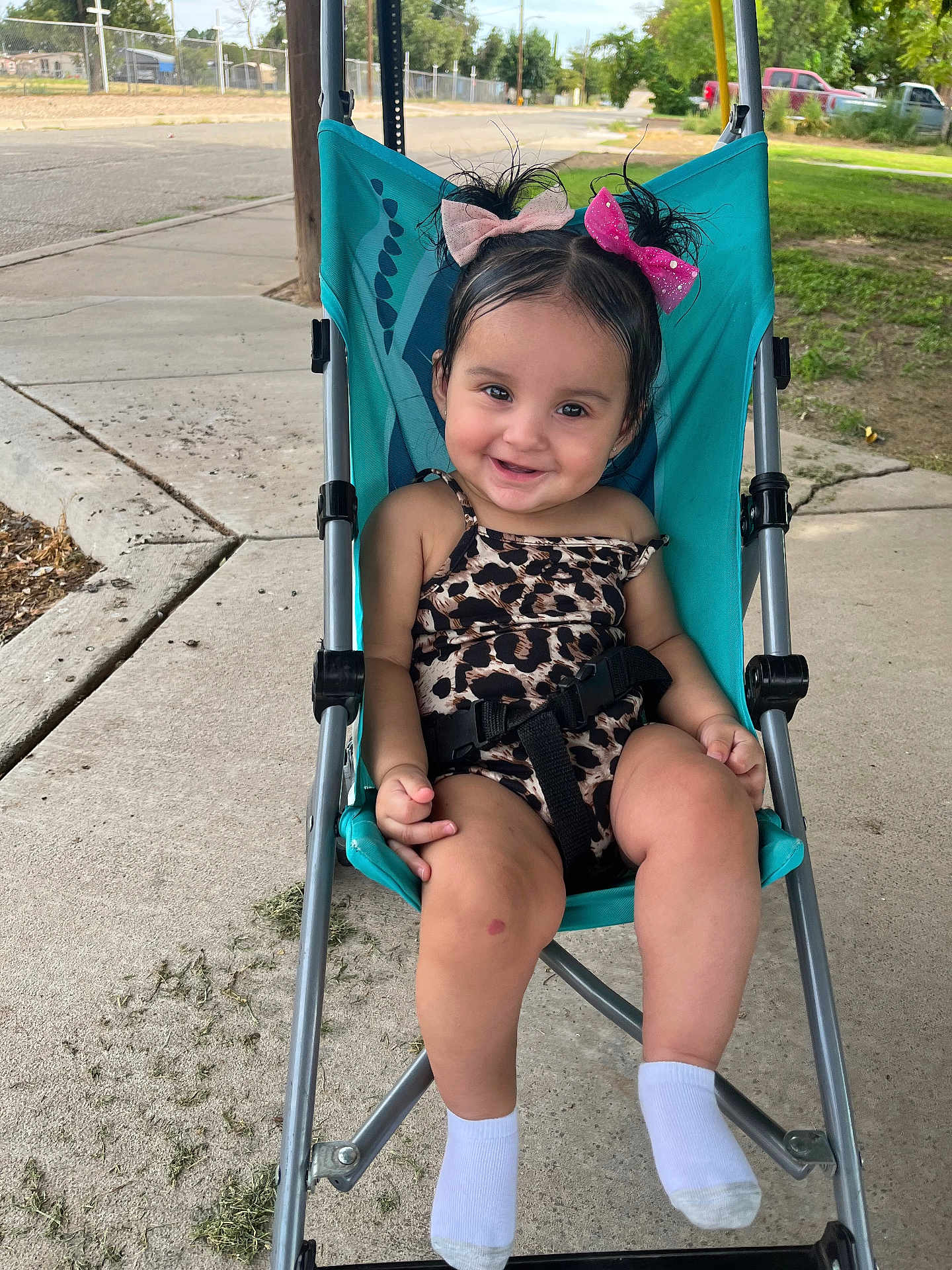 Jayselina joined the competition — help win amazing prizes! toddler, child, smiling, stroller, outdoor, sidewalk, leopard_print, hair_bows, white_socks, happy, cute, seatbelt, greenery, concrete, playful, young_child, portrait, baby, casual, sunlight