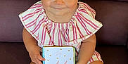 Lina a rejoint le concours — aidez-le/la à gagner de superbes lots ! baby, child, girl, blue_eyes, pink_bows, striped_outfit, sitting, couch, card, holding, smiling, shoes, legs, face, hair, indoors, cute, portrait, young_child, happy