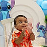 Josias is registered to the contest to win money with this photo: balloons, blue_balloons, cartoon_characters, celebration, chair, child, clapping, decorations, festive, happy, indoor, orange_shirt, party, photography, plant, portrait, smiling, stitch_cartoon, toddler, white_balloons