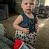 toddler, child, portrait, standing, indoors, living_room, smiling, facial_expression, blond_hair, blue_eyes, denim_top, patterned_pants, cow_print, sippy_cup, toy, carpet, sofa, storage_bins, window, sunlight