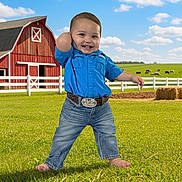 Gabriel is registered to the contest to win money with this photo: toddler, child, blue_shirt, jeans, barefoot, grass, farm, barn, red_barn, belt, smiling, happy, outdoor, sunny, clouds, cows, fence, hay_bale, greenery, portrait