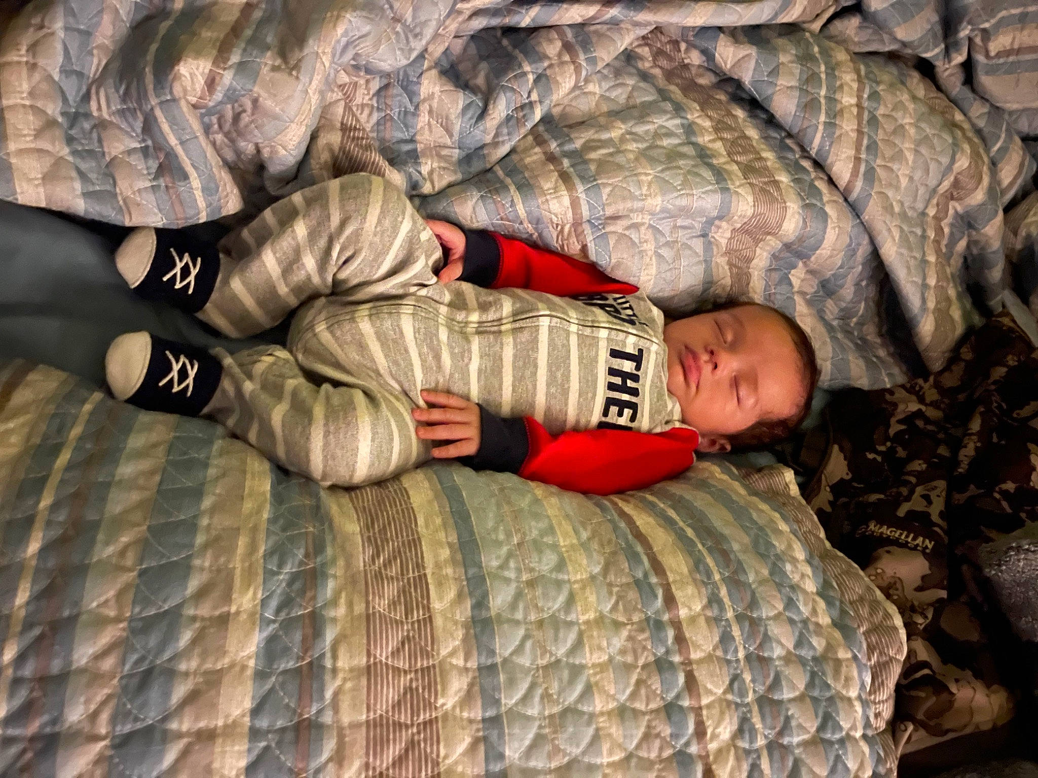 Cayden is registered to the contest to win money with this photo: arm, camouflage, child, comfort, couch, fur, gesture, hand, human_body, human_leg, leg, military_camouflage, military_uniform, pattern, person, room, sitting, textile, thigh, toddler
