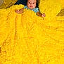 baby, infant, child, blanket, yellow_blanket, plush, pillow, bed, bedding, cozy, smile, face, head, onesie, arm, soft_texture, indoor, portrait, cute, home