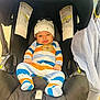 baby, infant, car_seat, onesie, striped_clothing, hat, blanket, stroller, buckle, harness, cute, smile, sitting, canopy, safety_label, footed_pajamas, hands, portrait, interior, cozy