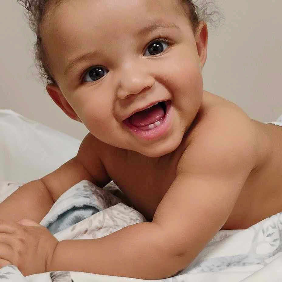 Oliver is registered to the contest to win money with this photo: baby, babylaughing, bed, bedroom, clothing, dress, face, furniture, happy, head, indoors, laughing, newborn, person, photography, portrait, quilt, room, smile