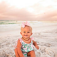 Ellarie is registered to the contest to win money with this photo: baby, child, beach, sand, ocean, sunset, sky, pink_bow, romper, smiling, sitting, cute, outdoor, nature, water, waves, portrait, happy, infant, summer