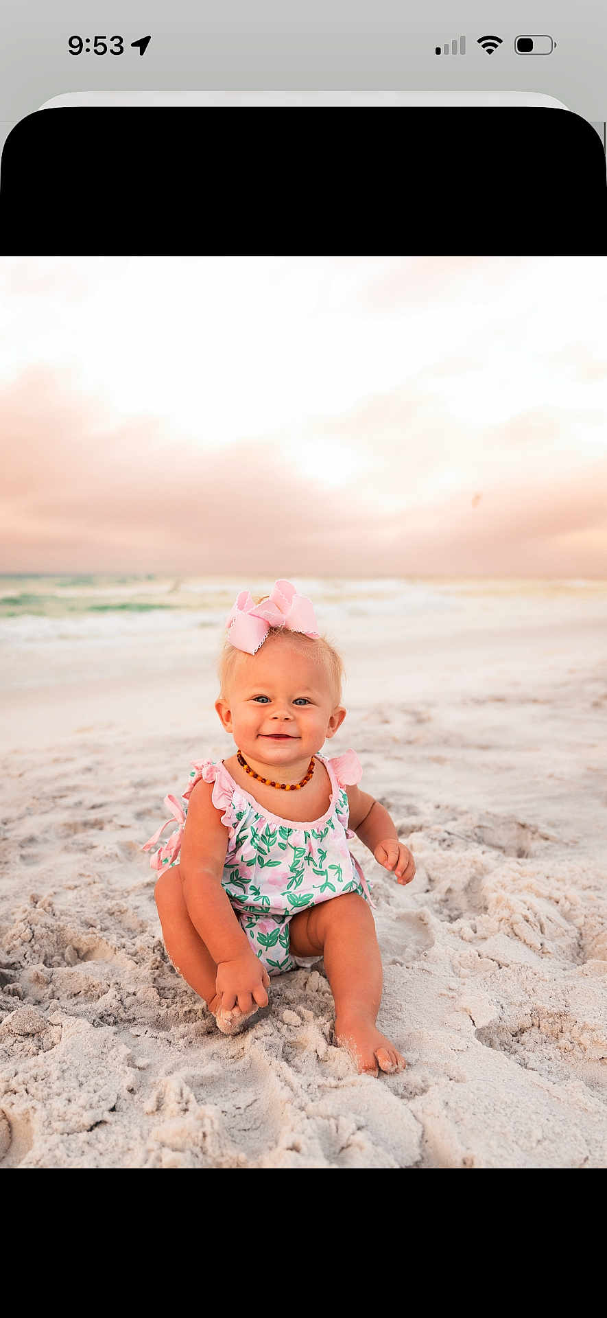Ellarie is registered to the contest to win money with this photo: baby, child, beach, sand, ocean, sunset, sky, pink_bow, romper, smiling, sitting, cute, outdoor, nature, water, waves, portrait, happy, infant, summer
