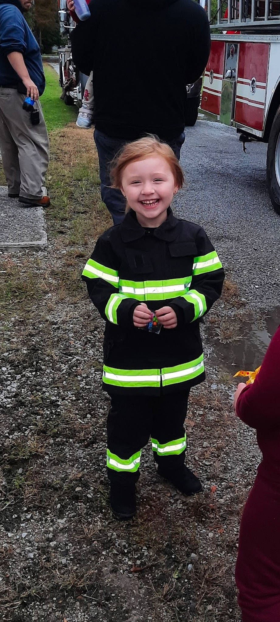 Brandy is registered to the contest to win money with this photo: asphalt, automotive_tire, blue_collar_worker, emergency_service, event, fire_department, firefighter, green, high_visibility_clothing, joy, motor_vehicle, outerwear, person, personal_protective_equipment, plant, public_utility, service, smile, tire, toddler