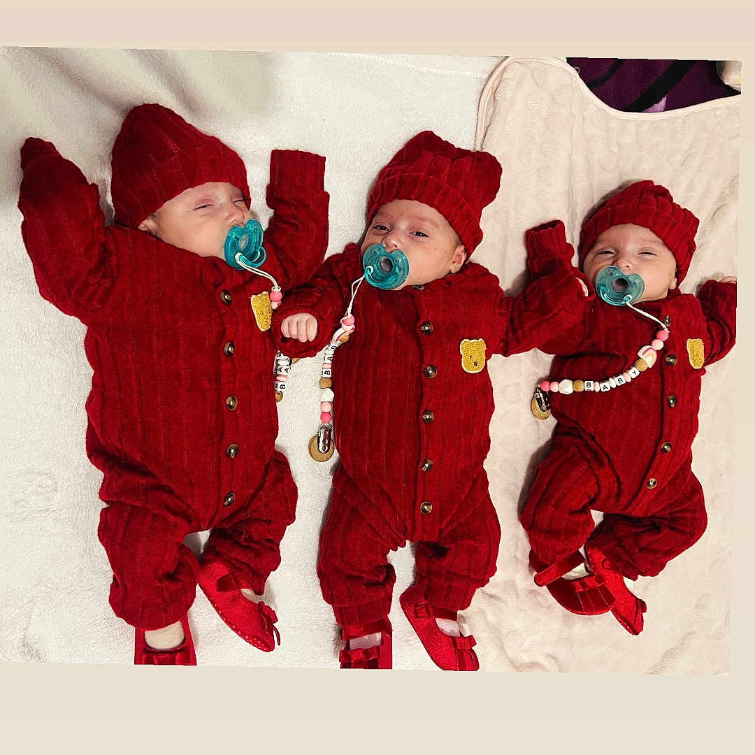 Luna Adela Elvana participe au concours pour gagner de l'argent avec cette photo : baby, bed, blanket, booties, cozy, cute, hands, infant, knitted_hat, lying_down, matching_outfits, newborn, nursery, pacifier, pacifier_chain, portrait, red_outfit, sibling, smile, triplets