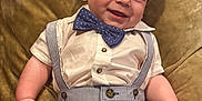 Langston joined the competition — help win amazing prizes! baby, child, smiling, bow_tie, suspenders, white_shirt, striped_shorts, plush_chair, indoor, happy, cute, portrait, infant, dressed_up, clothing, person, head, face, skin, sitting