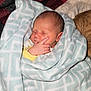 newborn, baby, sleeping, blanket, soft, hand, face, wrapped, cozy, indoor, pattern, yellow_clothing, infant, peaceful, cute, child, person, resting, warm, bed
