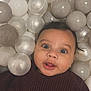 baby, child, face, smiling, sweater, ball_pit, balls, playful, indoor, cute, portrait, infant, person, happy, skin, head, eyes, mouth, clothing, young