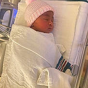 Kacey is registered to the contest to win money with this photo: architecture, baby, bed, blanket, bonnet, building, clothing, crib, furniture, hat, hospital, infantbed, newborn, person, sleeping