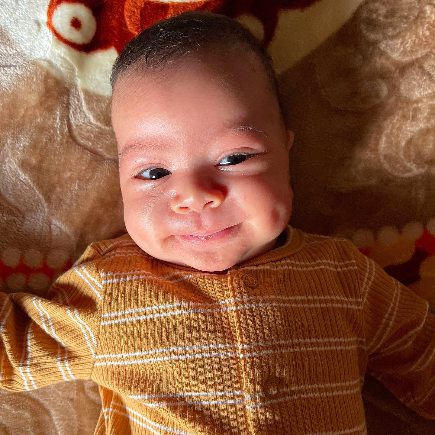 Haroon joined the competition — help win amazing prizes! baby, blanket, child, clothing, cozy, cute, expression, eyes, face, happy, indoor, infant, lying_down, patterned, portrait, skin, smiling, soft_lighting, striped, yellow