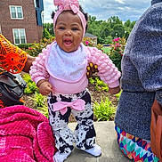 Shawty-Zuri joined the competition — help win amazing prizes! baby, toddler, child, outdoor, smiling, pink_headband, pink_top, cow_print_pants, bow, concrete, hand_support, plants, flowers, blanket, adult_hand, cloudy_sky, building, grass, person, colorful_clothing