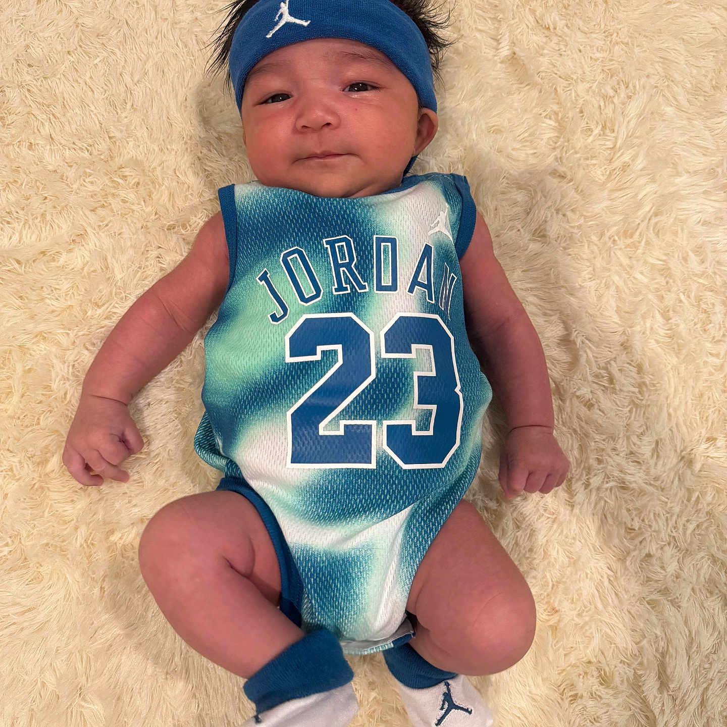 Aspen Julian is registered to the contest to win money with this photo: baby, blanket, blue, child, cute, face, faux_fur, hair, hands, headband, infant, jersey, jordan, legs, lying_down, number_23, portrait, socks, sportswear, white