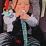 baby, car_seat, pacifier, dinosaur_pattern, striped_pants, infant, child, safety_harness, sunlight, shadow, white_shirt, sleeping, cute, closeup, indoors, seatbelt, comfort, adorable, peaceful, small_hands