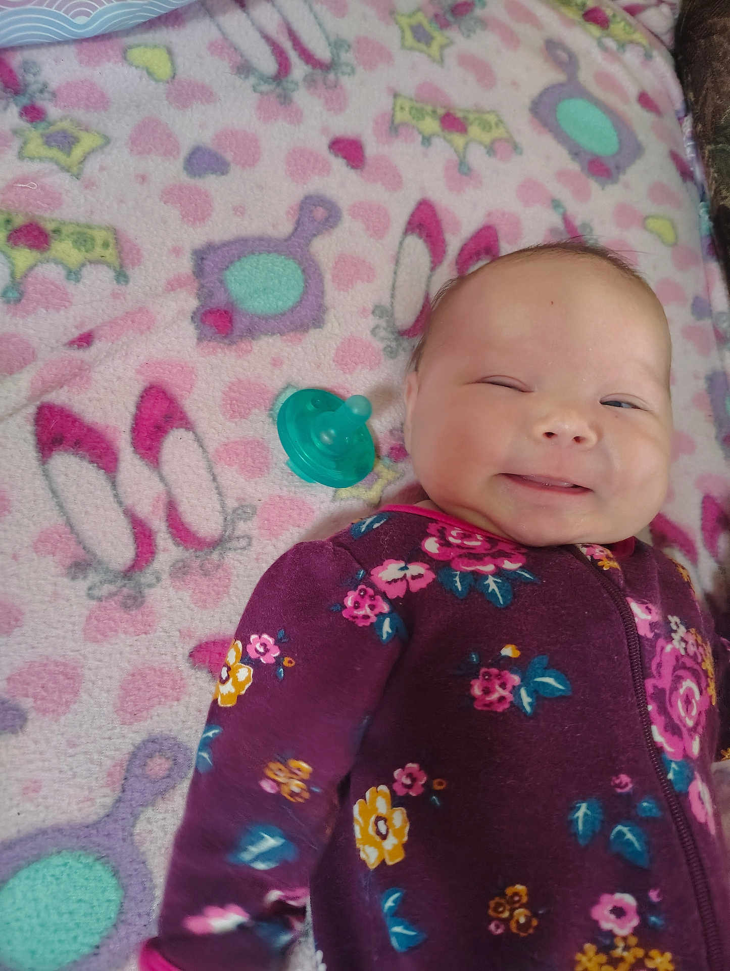 Raylynn joined the competition — help win amazing prizes! baby, smiling, floral_clothing, purple_onesie, blanket, colorful_blanket, animal_pattern, heart_pattern, lying_down, infant, cute, happy, indoors, child, face, head, pacifier, soft_texture, sleepwear, cozy