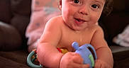 Lane Frost Chapman is registered to the contest to win money with this photo: baby, blanket, child, close_up, couch, curly_hair, cute, expression, face, hand, happy, indoor, infant, person, playful, skin, smiling, soft_focus, toddler, toy