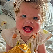 Jasmine joined the competition — help win amazing prizes! toddler, child, curly_hair, headband, bow, smiling, stuffed_animal, plush_toy, bedroom, bed, blanket, soft_lighting, happy, cute, infant, sitting, clothing, person, indoor, portrait