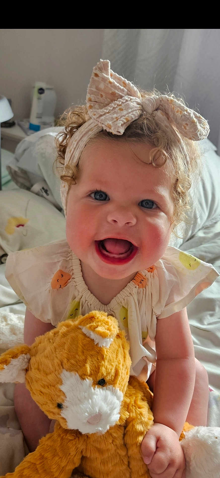 Jasmine joined the competition — help win amazing prizes! toddler, child, curly_hair, headband, bow, smiling, stuffed_animal, plush_toy, bedroom, bed, blanket, soft_lighting, happy, cute, infant, sitting, clothing, person, indoor, portrait