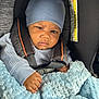 baby, child, blue_hat, car_seat, blanket, sweater, infant, seatbelt, face, hand, cozy, indoor, person, portrait, cute, clothing, car, safety, warm, expression