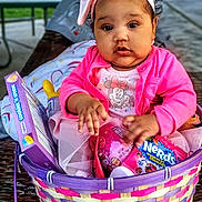 Novah joined the competition — help win amazing prizes! baby, child, infant, portrait, sitting, basket, easter_basket, candy, sweets, pink_clothing, headband, bow, minnie_mouse, outdoor, park, table, blurred_background, adorable, serious_expression, colorful