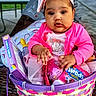 baby, child, infant, portrait, sitting, basket, easter_basket, candy, sweets, pink_clothing, headband, bow, minnie_mouse, outdoor, park, table, blurred_background, adorable, serious_expression, colorful