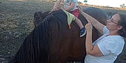 Noé participe au concours pour gagner de l'argent avec cette photo : child, toddler, horse, animal, outdoor, adult, woman, pacifier, grass, trees, sky, nature, person, clothing, field, holding, brown_horse, smile, daylight, fence