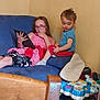 Noé participe au concours pour gagner de l'argent avec cette photo : child, children, couch, blue_couch, tablet, glasses, pink_dress, blue_shirt, red_shorts, toy, wooden_chair, indoor, living_room, floor, curious, sitting, playing, person, furniture, casual