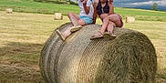 Cléa a rejoint le concours — aidez-le/la à gagner de superbes lots ! casual_clothing, child, children, cloudy_sky, farm, field, footwear, girl, grass, greenery, happy, hay_bale, nature, outdoor, peace_sign, playful, rural, sitting, sky, summer