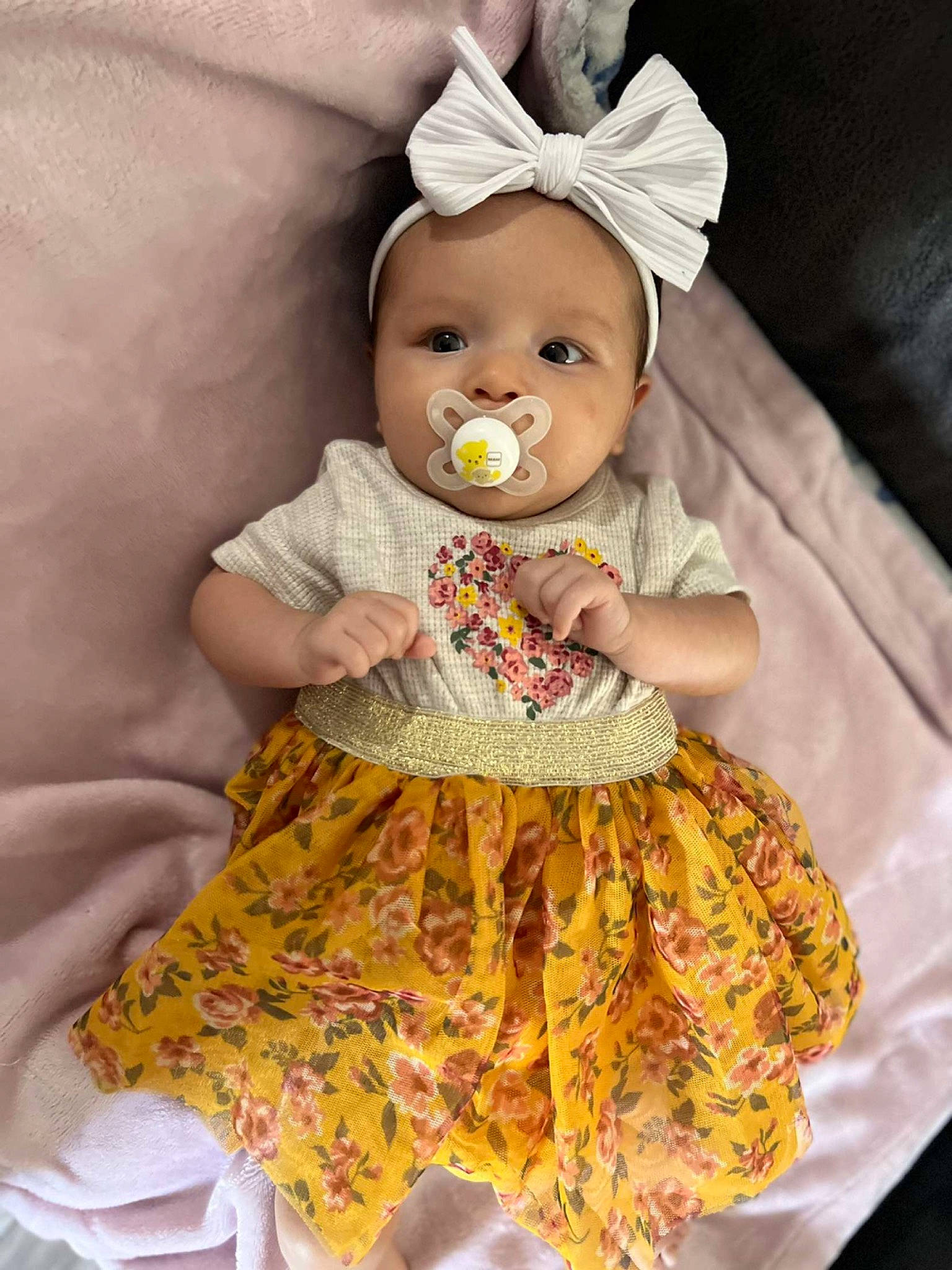 Gabriella is registered to the contest to win money with this photo: baby, baby_toddler_clothing, child, costume_hat, day_dress, doll, dress, embellishment, event, happy, pattern, peach, person, pink, ruffle, sitting, skin, sleeve, textile, toddler