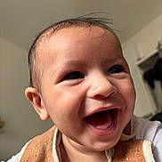 Keïron a rejoint le concours — aidez-le/la à gagner de superbes lots ! baby, smiling, face, infant, close_up, indoors, happy, child, apparel, bib, skin, head, expression, person, cute, young, portrait, mouth_open, cheerful, hair