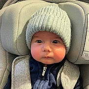 Simon a rejoint le concours — aidez-le/la à gagner de superbes lots ! baby, child, infant, car_seat, hat, knit_hat, jacket, zipper, seatbelt, face, cute, indoors, warm_clothing, straps, headwear, person, portrait, young_child, closeup, expression