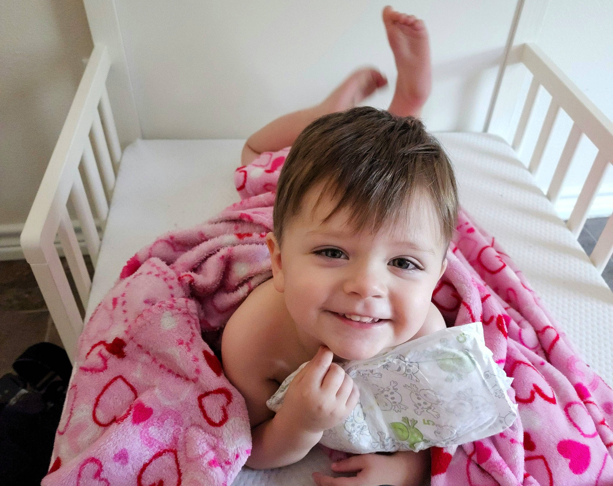 Justyn is registered to the contest to win money with this photo: baby, baby_products, baby_toddler_clothing, cheek, child, comfort, eyelash, fashion_accessory, finger, gesture, happy, joy, linens, magenta, pattern, person, pink, room, skin, smile