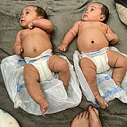 Twins is registered to the contest to win money with this photo: baby, infant, diaper, plastic_bag, blanket, feet, furniture, floor, person, skin, lying_down, indoor, carpet, head, face, newborn, cute, child, two_people, resting