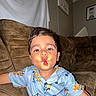 child, toddler, baby, portrait, face, smiling, puckering, kissy_face, sitting, couch, sofa, pajamas, cartoon_clothing, blue_clothing, indoor, living_room, furniture, flash_photography, brown_couch, home