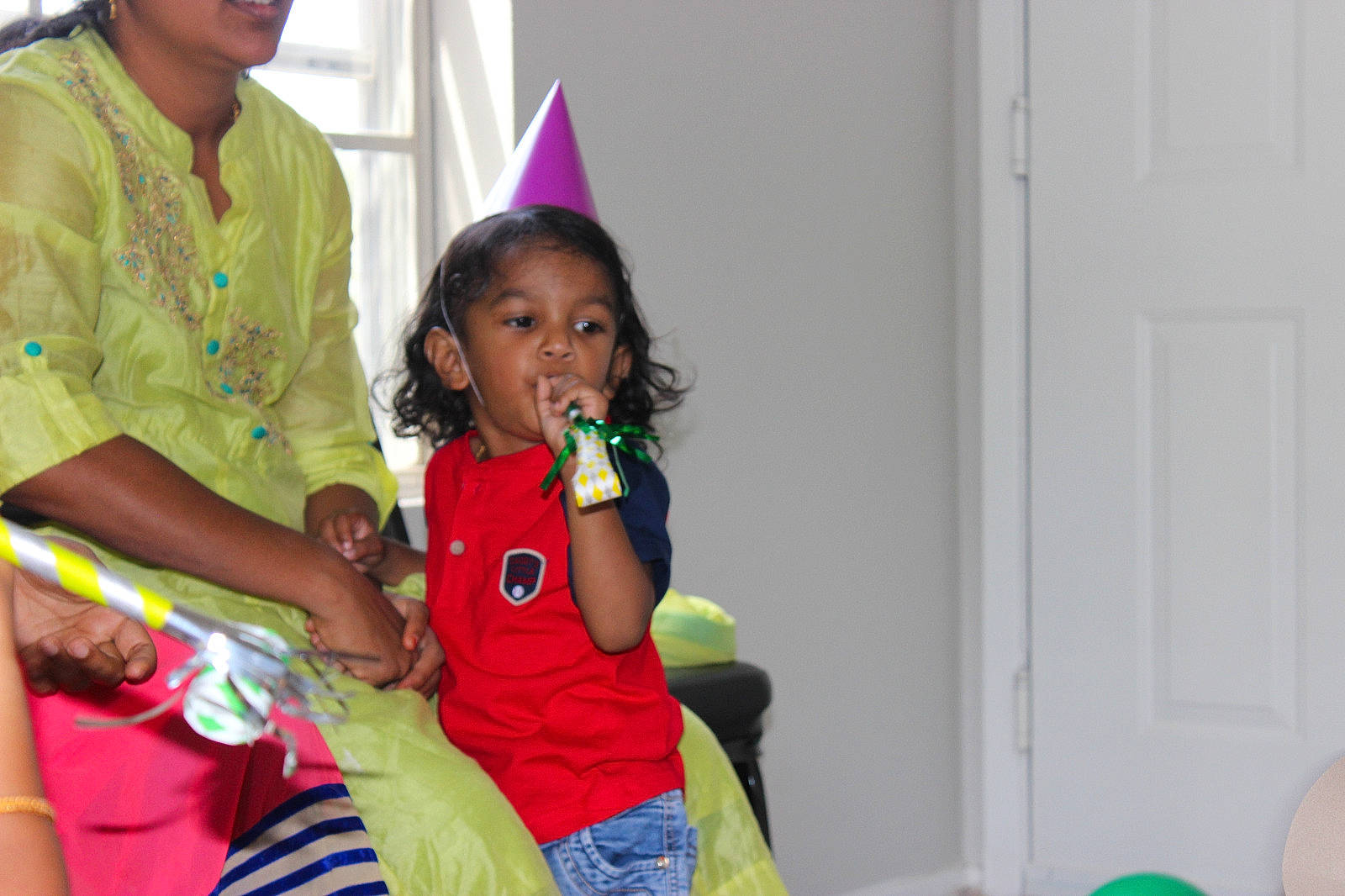 Nethran is registered to the contest to win money with this photo: balloon, birthday, child, door, event, facial_expression, fun, hairstyle, happy, kindergarten, leisure, magenta, party, party_supply, person, room, sharing, sitting, t_shirt, toddler