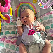 Nevaeh is registered to the contest to win money with this photo: baby, infant, baby_seat, rainbow, toy, mittens, sunlight, indoor, colorful, happy, child, cute, patterned_fabric, playtime, closeup, smiling_sun, hanging_toy, pink, yellow, purple