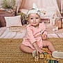 toddler, child, pink_dress, headband, wooden_blocks, rug, cushions, plants, boho_decor, indoor, floor, playtime, smiling, cute, baby, toy_blocks, white_shoes, woven_rug, cozy, portrait
