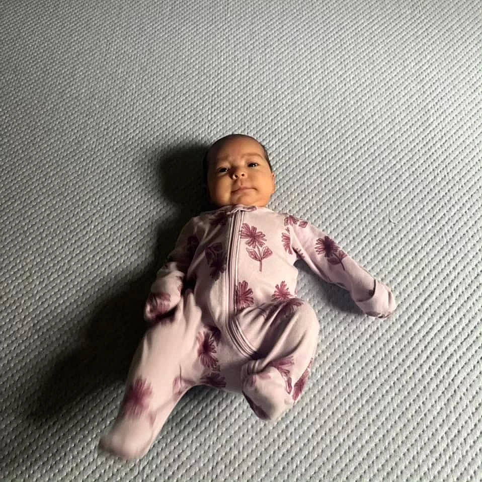 Audrey is registered to the contest to win money with this photo: baby, baby_toddler_clothing, barefoot, carmine, comfort, doll, flesh, flooring, foot, gesture, happy, head, headwear, human_body, human_leg, nail, person, sitting, sleeve, thumb