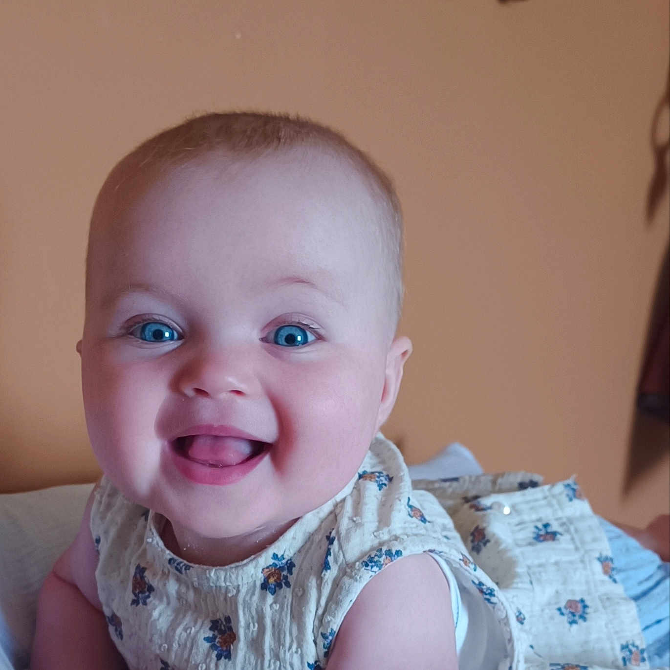 Margot participe au concours pour gagner de l'argent avec cette photo : baby, blue_eyes, cheerful, child, closeup, cute, face, floral_dress, happy, indoors, infant, lying_down, person, portrait, skin, smiling, soft_lighting, toddler, warm_background, white_surface