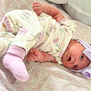 Sienna is registered to the contest to win money with this photo: baby, infant, pajamas, headband, bow, bed, bedding, pattern, floral, pink, lavender, sock, lying_down, cute, soft, child, newborn, face, skin, sleepwear