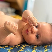 Mateo a rejoint le concours — aidez-le/la à gagner de superbes lots ! baby, infant, child, bare_skin, face, eyes, hand, fist, lying_down, blanket, pattern, blue, yellow, indoors, closeup, portrait, curious, cute, soft_light, skin