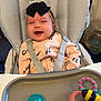 baby, infant, high_chair, headband, black_bow, onesie, smiling, tray_table, pacifier, teething_toy, harness, seat_cushion, patterned_fabric, indoor, feeding_time, happy, water_dispenser, baby_accessory, small_person, portrait