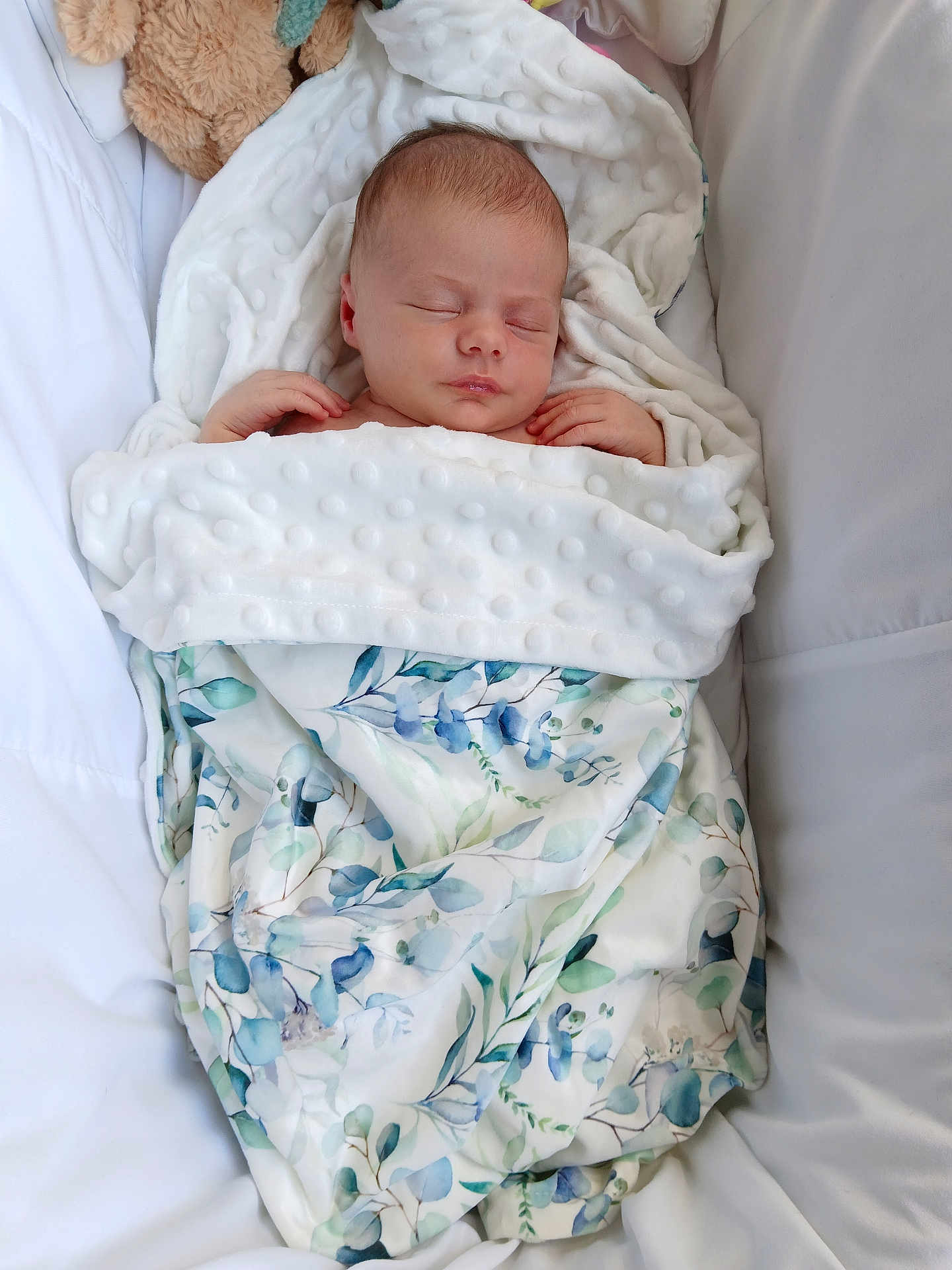 Tabitha joined the competition — help win amazing prizes! newborn, baby, sleeping, blanket, floral_pattern, crib, plush_toy, teddy_bear, soft_texture, white, blue, green, peaceful, infant, wrapped, cozy, comfortable, portrait, indoors, resting