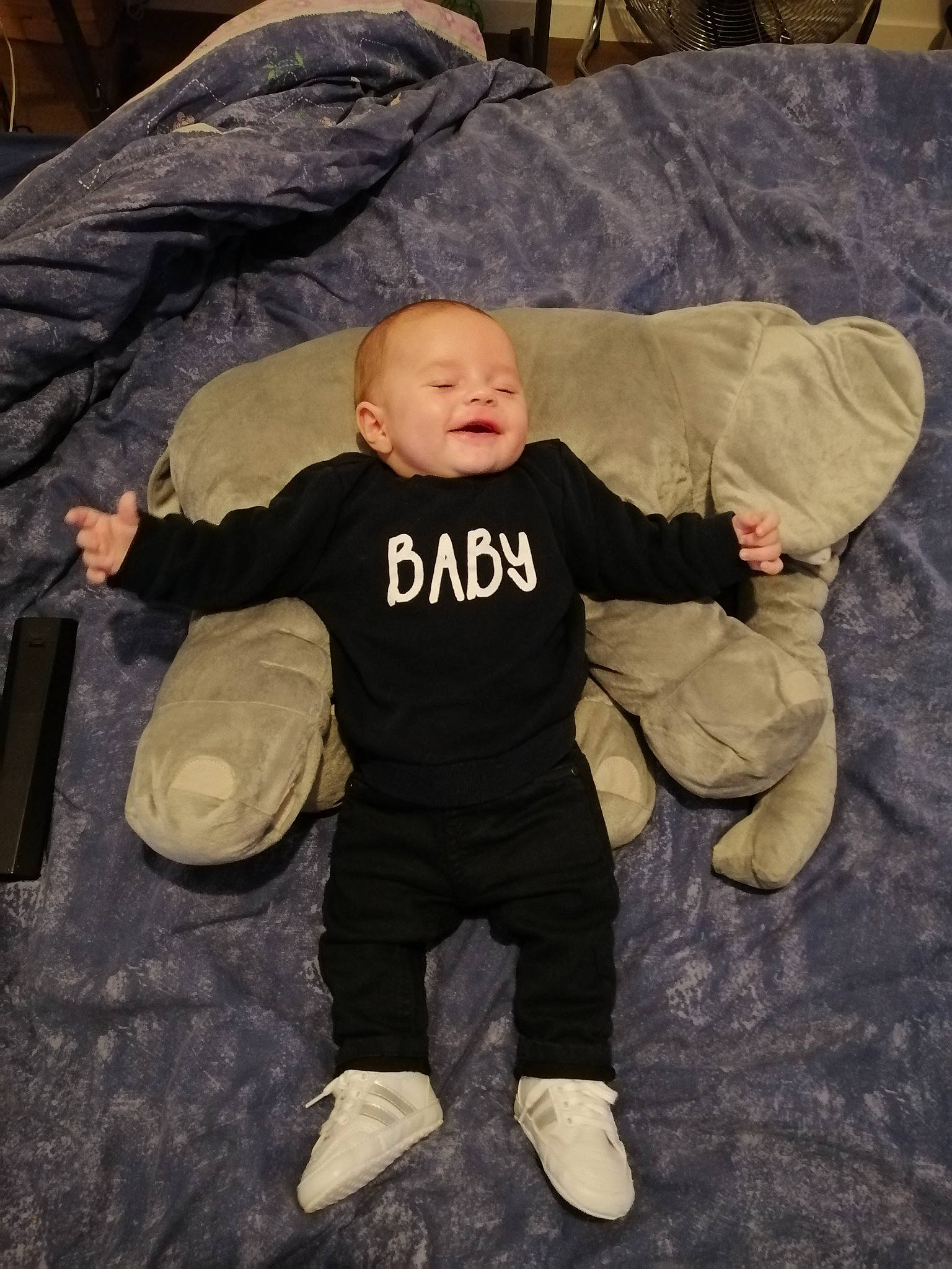 Soann participe au concours pour gagner de l'argent avec cette photo : baby, baby_toddler_clothing, brown, child, comfort, eye, flooring, fun, happy, person, room, sitting, sleeve, smile, t_shirt, toddler, wood